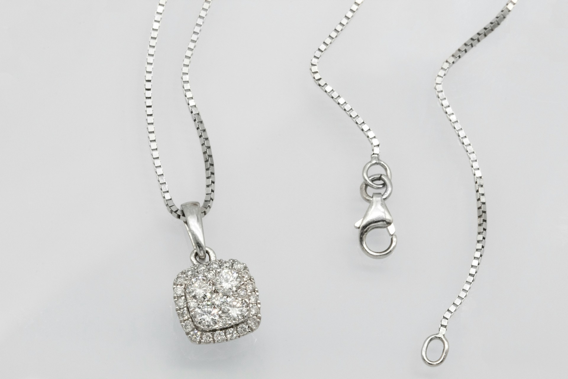 a platinum and diamond chain pendant on a gray background