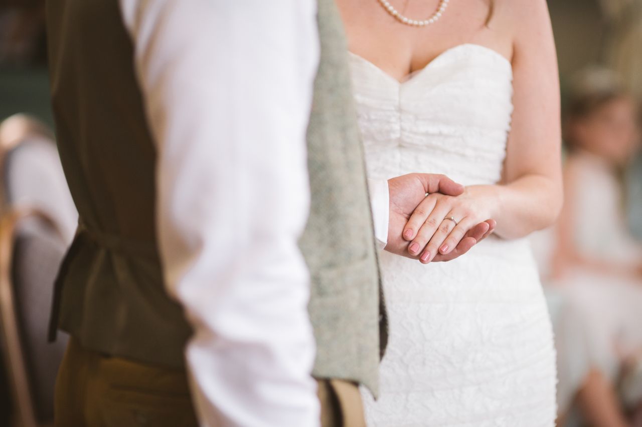 a bride holds hands with her groom at their ceremony.