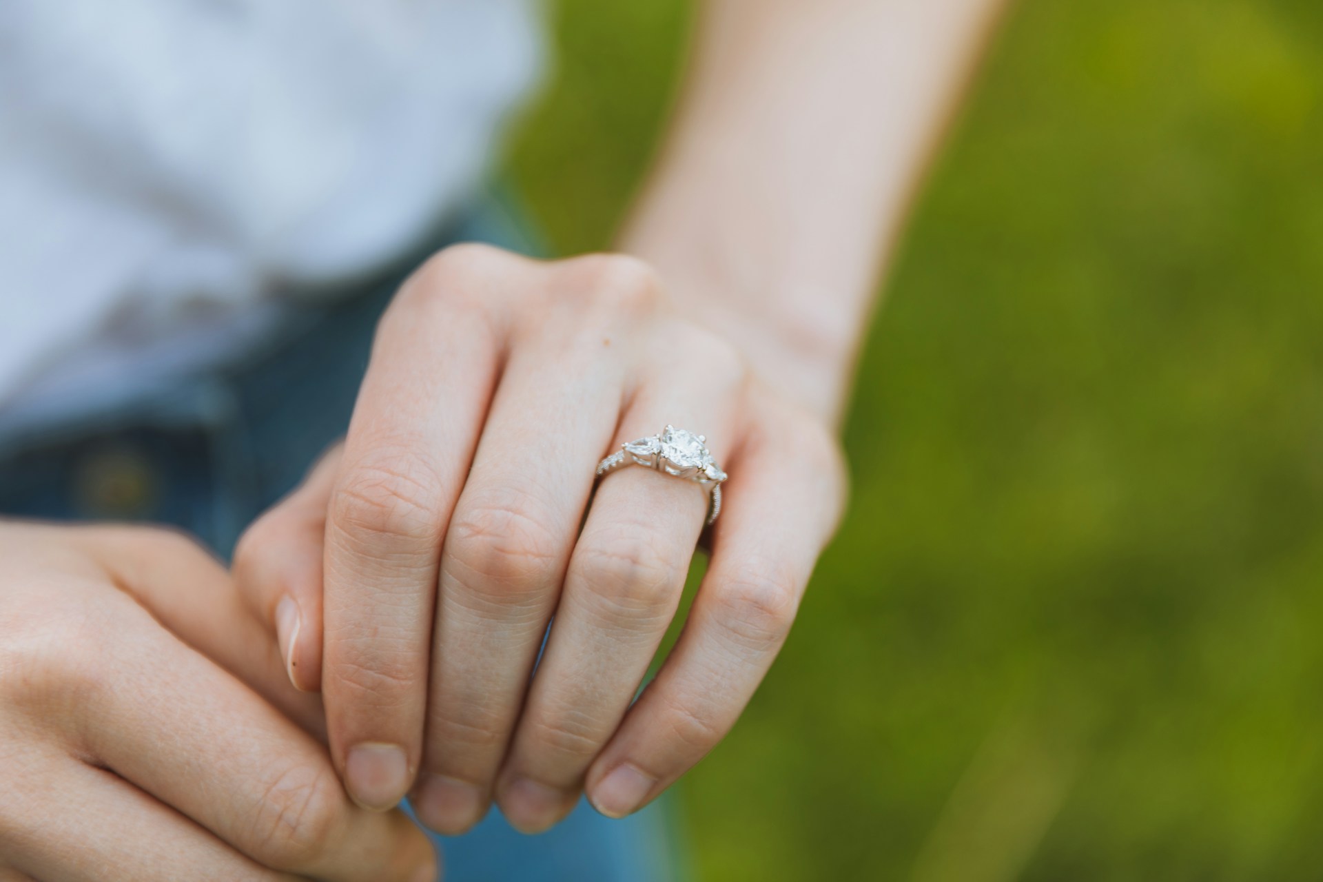 A close-up of a woman’s hand adorned with an elegant engagement ring.