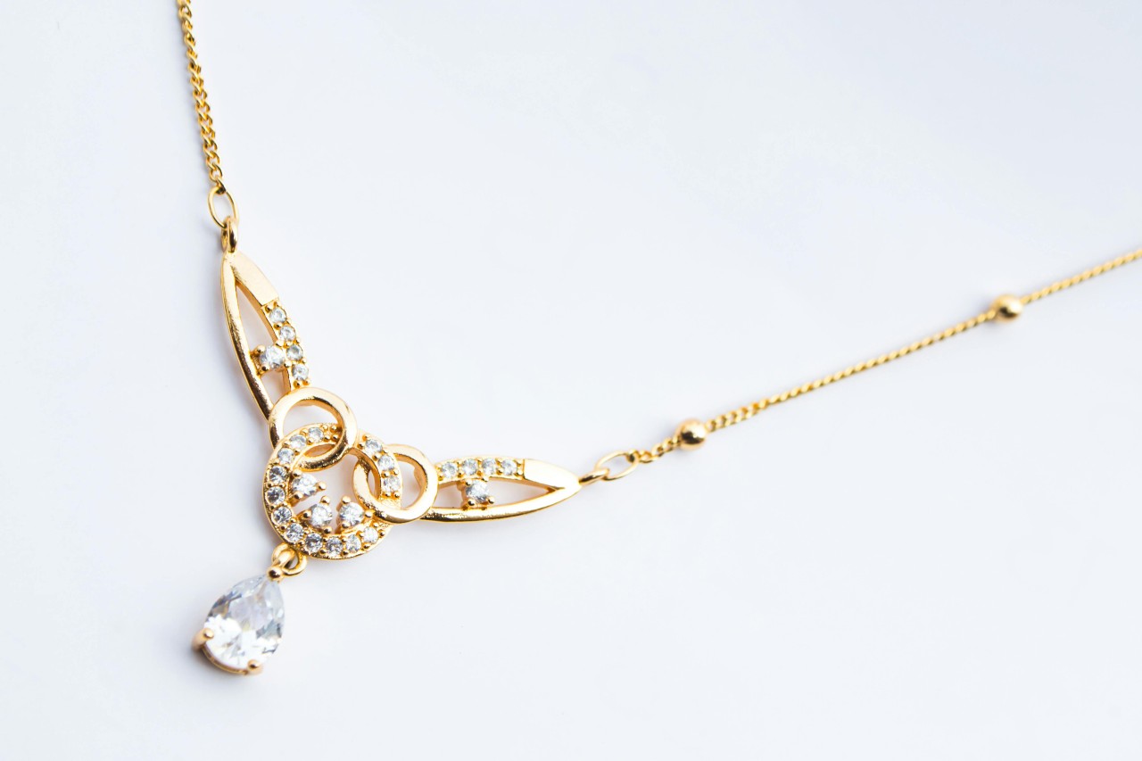 a yellow gold diamond pendant necklace with intricate details and diamond accents