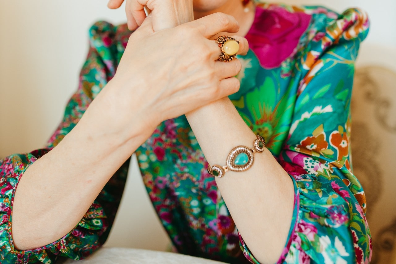 a woman in a patterned blouse wearing a bracelet featuring turquoise and other gems