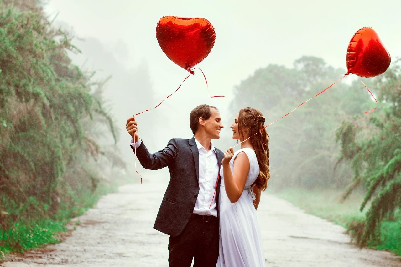 A couple with red heart balloons on Valentine’s Day