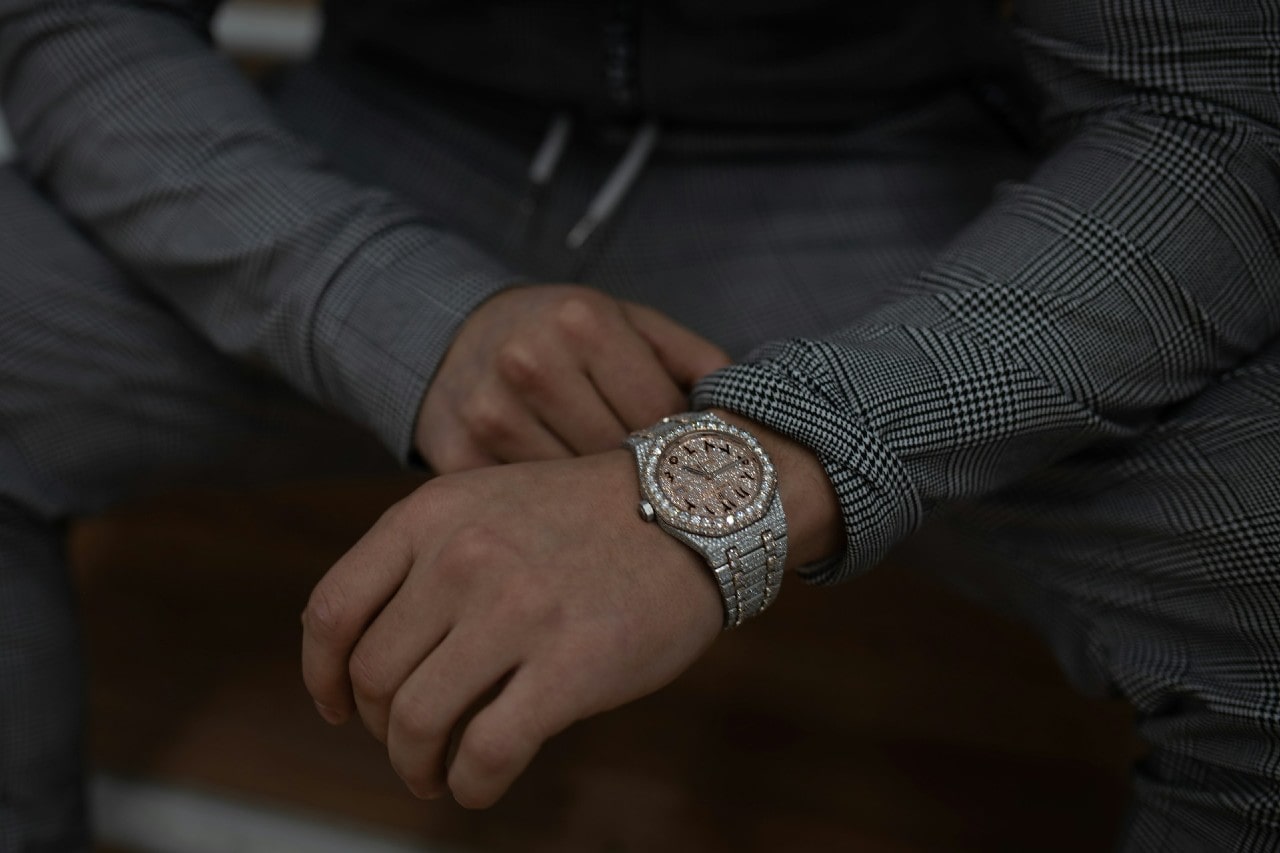 a person in a gray suit wearing an elaborate, diamond studded watch