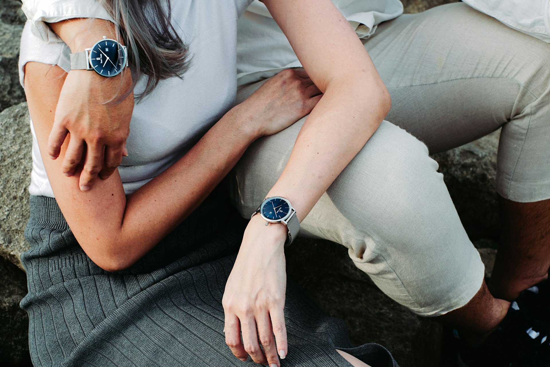 a couple embracing, both wearing silver watches with blue dials