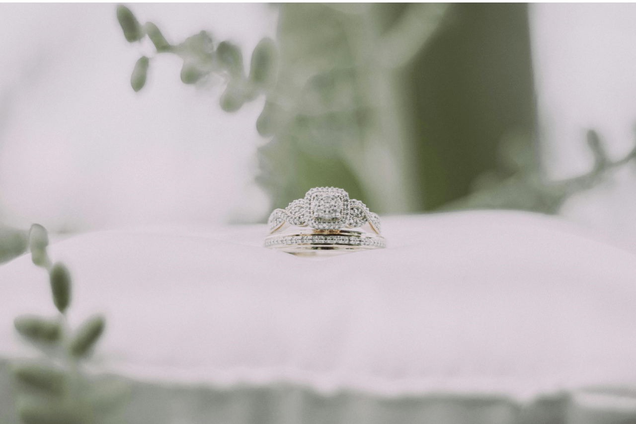 an elaborate engagement ring and wedding band sitting on a white pillow