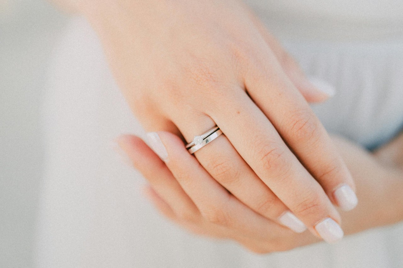 a woman’s hands – wearing a simple white gold engagement ring and wedding band