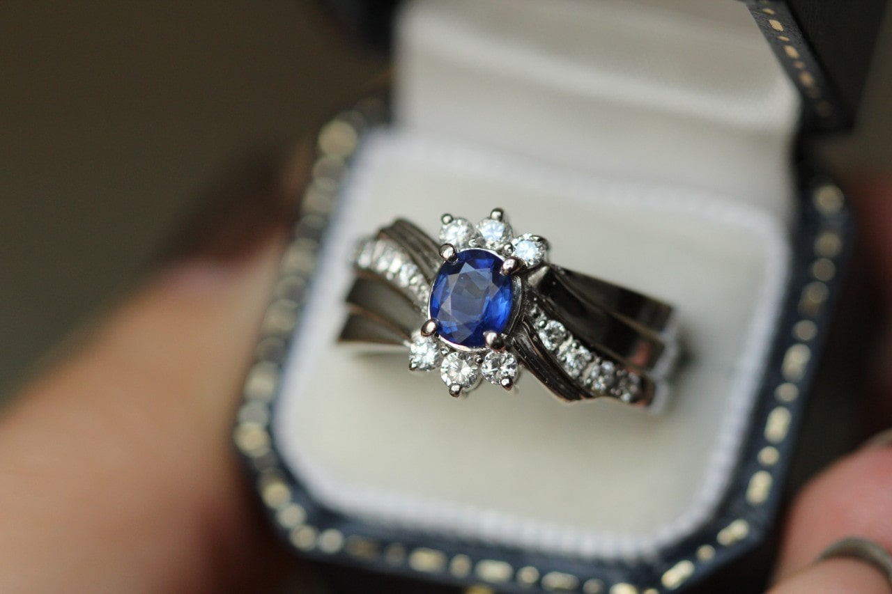 a statement ring featuring diamonds and round cut blue sapphire in a ring box