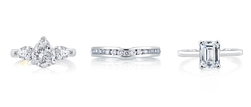 Two white gold engagement rings flanking a platinum channel wedding band by A.JAFFE