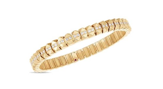 A gold bangle bracelet with geometric details and diamond accents