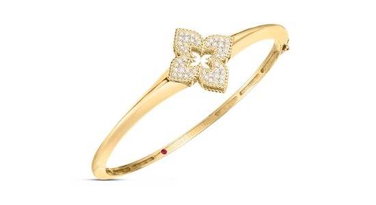 A gold bangle bracelet with a stylized flower motif dotted with round cut diamonds