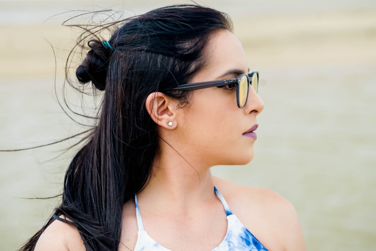 A woman with a half updo wears radiant diamond studs with a tie-dye tank top.