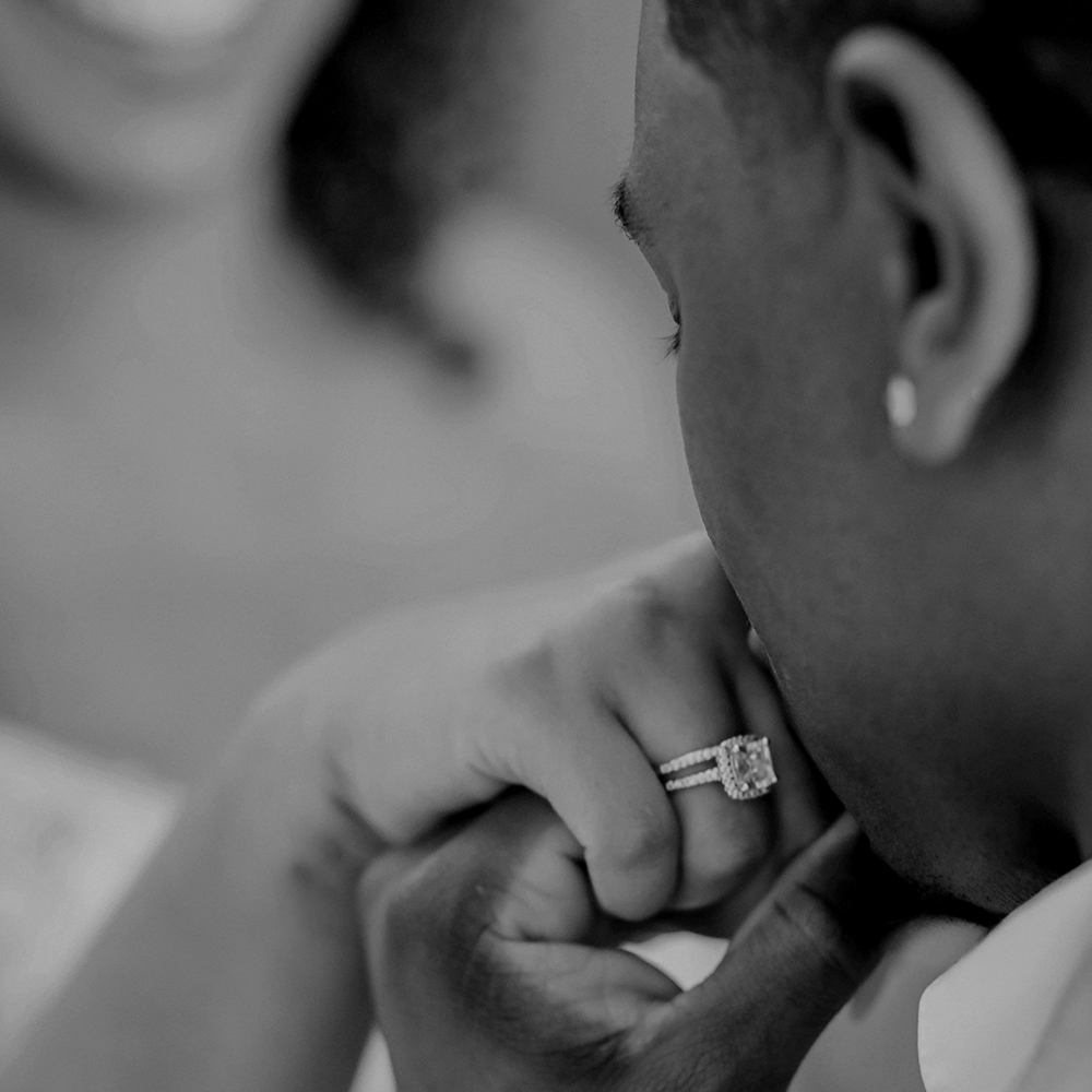 man kissing a woman's hand with an engagement ring