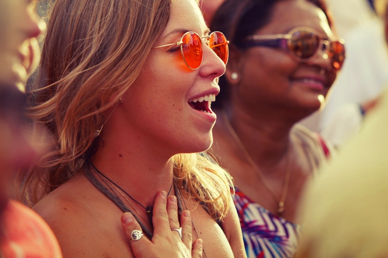 A woman in a crowd at a summer festival wears jewelry.