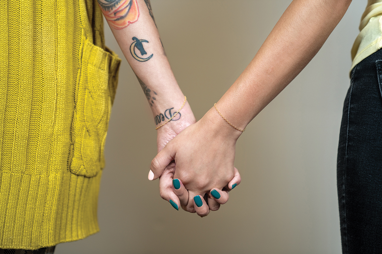 two girls hold hands with permanent bracelets on their wrists