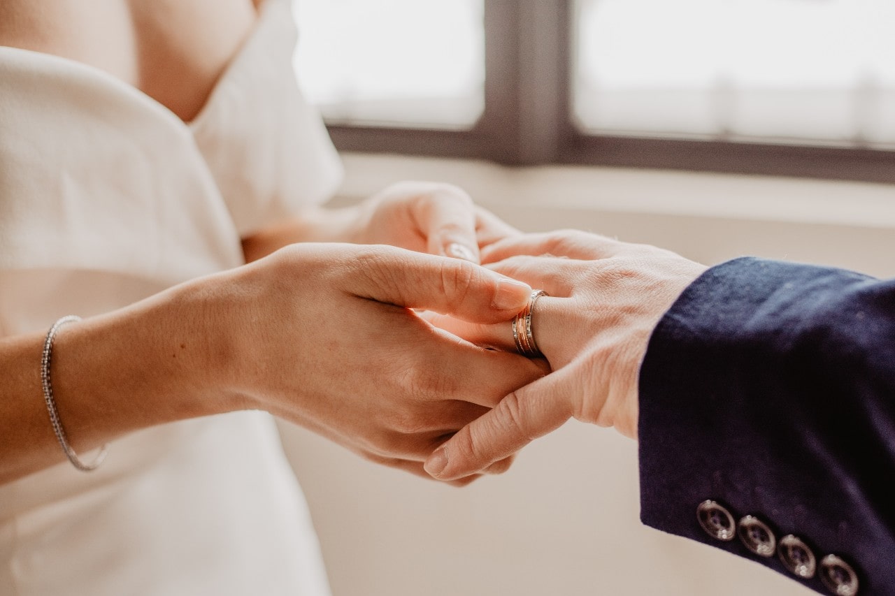 a bride putting a wedding ring on her groom